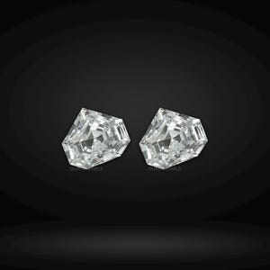 May include: Two loose, colorless, shield-cut gemstones with a faceted surface that reflects light. Each stone features a geometric, multi-sided shape with a pointed top and a flat base. The text OUROS JEWELS is printed in small letters below each stone.