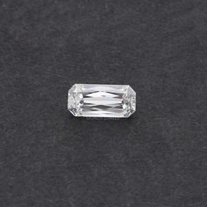 May include: A clear, rectangular emerald cut diamond gemstone with facets.
