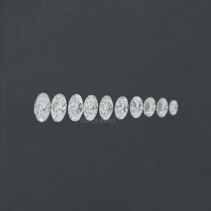 May include: A row of oval-shaped diamonds of varying sizes, arranged from largest to smallest, on a black background. The diamonds are clear and sparkly.