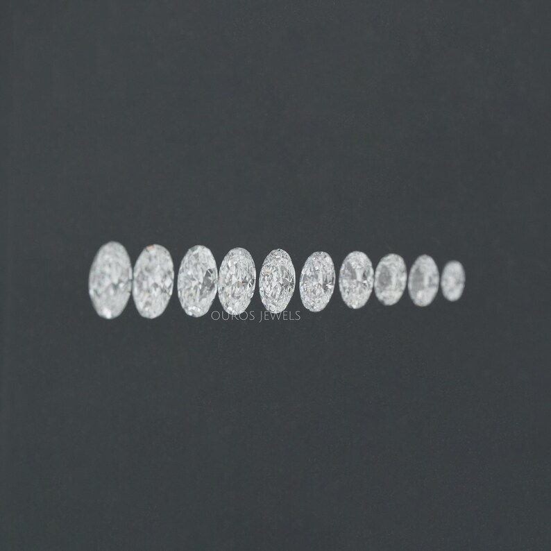 May include: A row of oval-shaped diamonds of varying sizes, arranged from largest to smallest, on a black background. The diamonds are clear and sparkly.