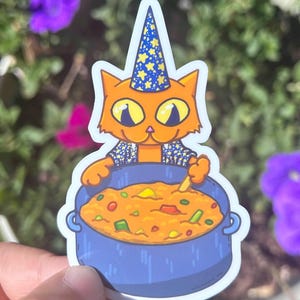 May include: A sticker featuring an orange cat wearing a blue wizard hat with yellow stars, stirring a pot of stew. The cat has yellow eyes and is wearing a blue and white patterned shirt. The stew is orange with green and red vegetables.