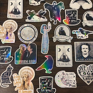May include: A collection of holographic stickers featuring various designs, including crows, ravens, moons, and tarot cards. The stickers have a glittery, iridescent finish and feature text such as "Nevermore", "Crow Before Bros", "The High Priestess", and "Rock on Gold Dust Woman".