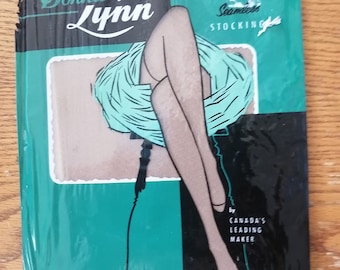 Puede incluir: Un paquete vintage de medias sin costuras Donna Lynn, con una mujer con las piernas en un fondo azul verdoso y negro. El texto del paquete dice "Donna Lynn Seamless Stocking by Canada's Leading Maker. Sheer Beauty - Proportionated to Fit."