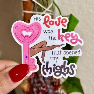 May include: A sticker with a pink heart-shaped key design and the text "His love was the key that opened my thighs." The sticker features a cartoon illustration of legs.