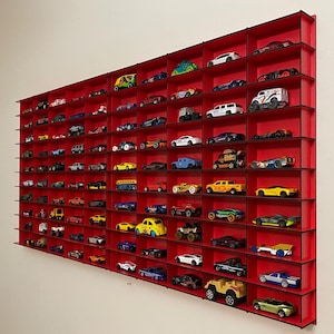 May include: A red wall shelf with multiple compartments, each holding a toy car. The shelf is filled with a variety of toy cars in different colors and styles.