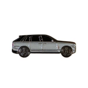 May include: A silver and black SUV pin with detailed chrome wheels. The pin features a two-tone design with a black roof and silver body, showcasing a luxury vehicle.