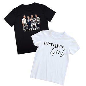 May include: Two t-shirts. One black t-shirt features a group of men with the word "WESTLIFE" in white. The other is a white t-shirt with the words "UPTOWN Girl" in black script.