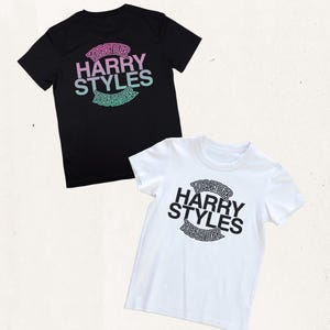 May include: A black t-shirt and a white t-shirt, each featuring a circular graphic with the text TOGETHER HARRY STYLES TOGETHER. The black shirt has a pink and light blue gradient print, while the white shirt has a solid black print.
