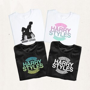 May include: Four t-shirts featuring Harry Styles graphics. Two white shirts, one with a black silhouette of a person sitting on a disco ball and one with pink, purple, and teal text. Two black shirts with green or white text reading TOGETHER HARRY STYLES.