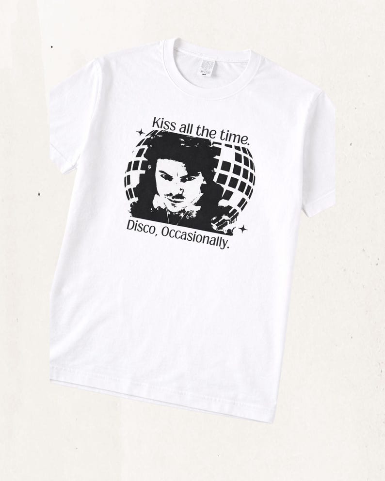 May include: A white short-sleeve t-shirt featuring a black graphic print of a person in front of a disco ball. The text above the graphic reads Kiss all the time. and the text below the graphic reads Disco, Occasionally. with small star icons.