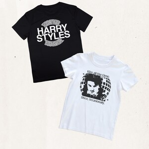 May include: A black t-shirt with white text reading "TOGETHER HARRY STYLES TOGETHER" and a white t-shirt featuring a black graphic of a person in front of a disco ball with the text "Kiss all the time. Disco, Occasionally." printed above and below.