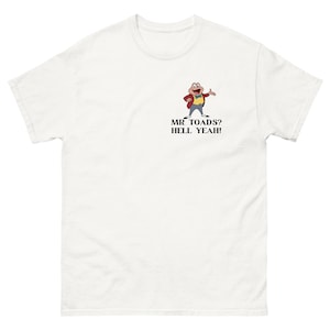 May include: White t-shirt with a cartoon frog in a red jacket and bow tie. The text "MR TOADS? HELL YEAH!" is printed below the frog. The shirt has a crew neck and short sleeves, a classic casual style.