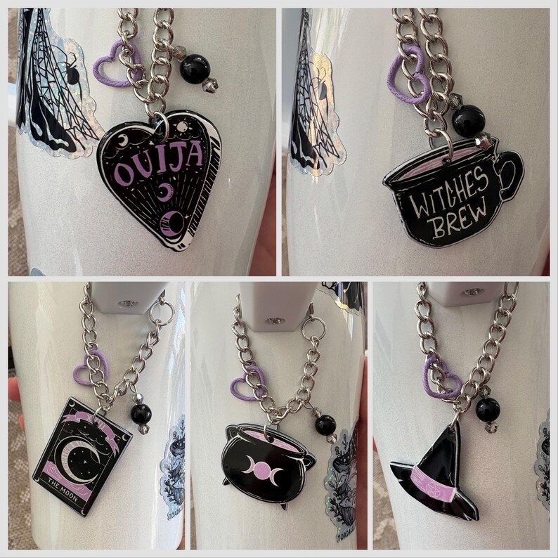 May include: Four white mugs with black and purple charms attached to silver chains. The charms include a Ouija board, a cauldron, a witch's hat, and a cup that says "Witches Brew".