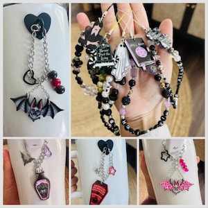 May include: Four white mugs with different charms attached to them. The charms include a bat, a potion bottle, a coffin, and a bat with pink accents. The charms are attached to the mugs with a silver chain and a black hook.