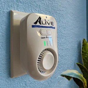 May include: A white ozone therapy spa device with the word "Alive" in black lettering. The device has a knob, two buttons, and a green light. The device is plugged into a wall socket.