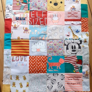 May include: A colorful patchwork quilt made from baby clothes with various patterns and designs. The quilt features a variety of characters including Mickey Mouse, Winnie the Pooh, and a bunny rabbit. The quilt also includes text such as "ELF SIZED", "LOVE YOU MUMMY", and "Mejor Papa del Mundo".