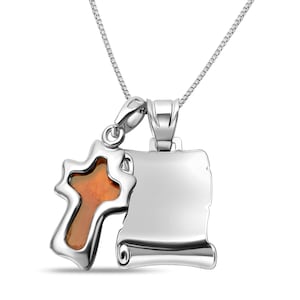 Peut inclure: Un collier pendentif argenté avec une croix au centre ambré et un charm en forme de parchemin. La chaîne du collier est fine, le tout sur fond blanc.