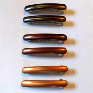 May include: Six hair clips in two different colors. Two are black, two are brown, and two are a lighter brown color.