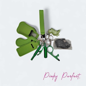 May include: A selection of green keychains and accessories, including a hand sanitiser holder, a dinosaur charm, a bottle opener, and a touch-free door opener. The items are attached to silver keyrings.