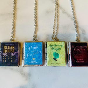 May include: Four silver-toned necklaces each feature a miniature book pendant. The book covers display titles like "Bleak House" and "Pride and Prejudice." The pendants are rectangular with a silver border and attached to a delicate chain.