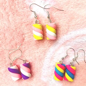 K&ouml;nnte beinhalten: Vier Paar bunte, marshmallowf&ouml;rmige Ohrringe. Die Ohrringe weisen eine Vielzahl von Farben auf, darunter Gelb, Rosa, Wei&szlig;, Lila, Blau und Pink. Die Ohrringe sind mit silberfarbenen Haken versehen.