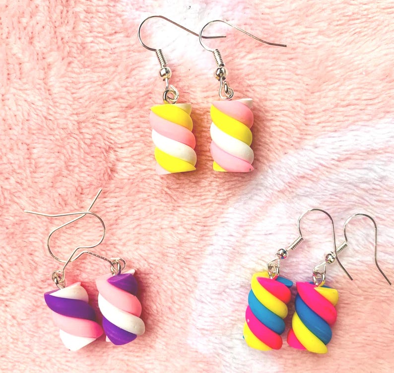 K&ouml;nnte beinhalten: Vier Paar bunte, marshmallowf&ouml;rmige Ohrringe. Die Ohrringe weisen eine Vielzahl von Farben auf, darunter Gelb, Rosa, Wei&szlig;, Lila, Blau und Pink. Die Ohrringe sind mit silberfarbenen Haken versehen.