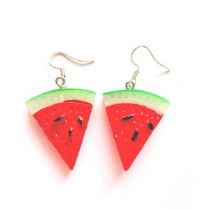 K&ouml;nnte beinhalten: Ein Paar Ohrringe in Form von Wassermelonenst&uuml;cken. Jeder Ohrring hat ein rotes, wei&szlig;es und gr&uuml;nes Design mit schwarzen Samendetails. Die Ohrringe haben silberfarbene Fischhaken-Ohrdr&auml;hte.