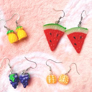 K&ouml;nnte beinhalten: Vier Paar ausgefallene Ohrringe mit Fruchtdesign. Enth&auml;lt gelbe Ananas, rote Wassermelonenst&uuml;cke, lila Trauben und orangefarbene Mandarinen-Ohrringe. Jedes Paar hat einen silberfarbenen Haken.