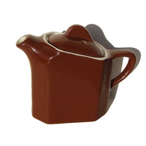 May include: A brown ceramic teapot with a square body and a curved handle. The teapot has a lid with a small knob and a white rim. The spout is white. The teapot is likely used for brewing tea.
