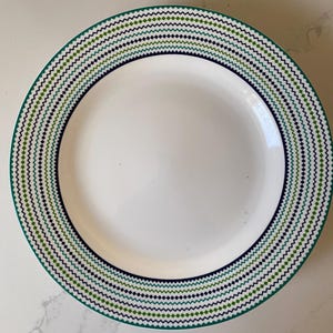 May include: White ceramic dinner plate with a green, blue, and white geometric pattern around the rim.