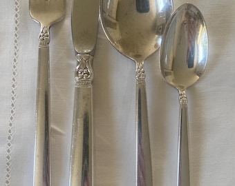 May include: Set of four silver-plated flatware pieces, including a fork, knife, soup spoon, and teaspoon. The handles have an ornate design with a floral motif.