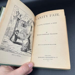 May include: Open book titled "Vanity Fair" by William Makepeace Thackeray. The book's pages are aged with visible text and illustrations. The cover is green. The illustration depicts a farewell scene.