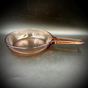 May include: A white ceramic mug with a black handle and the text "But First, Coffee" in a bold, black font. The mug is set against a blurred background, suggesting a cozy setting.