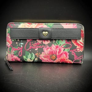 May include: A black wallet with a floral pattern of pink, red, and green flowers. The wallet has a black bow with a gold heart-shaped clasp. The words "Juicy Couture" are written on the wallet in pink script.