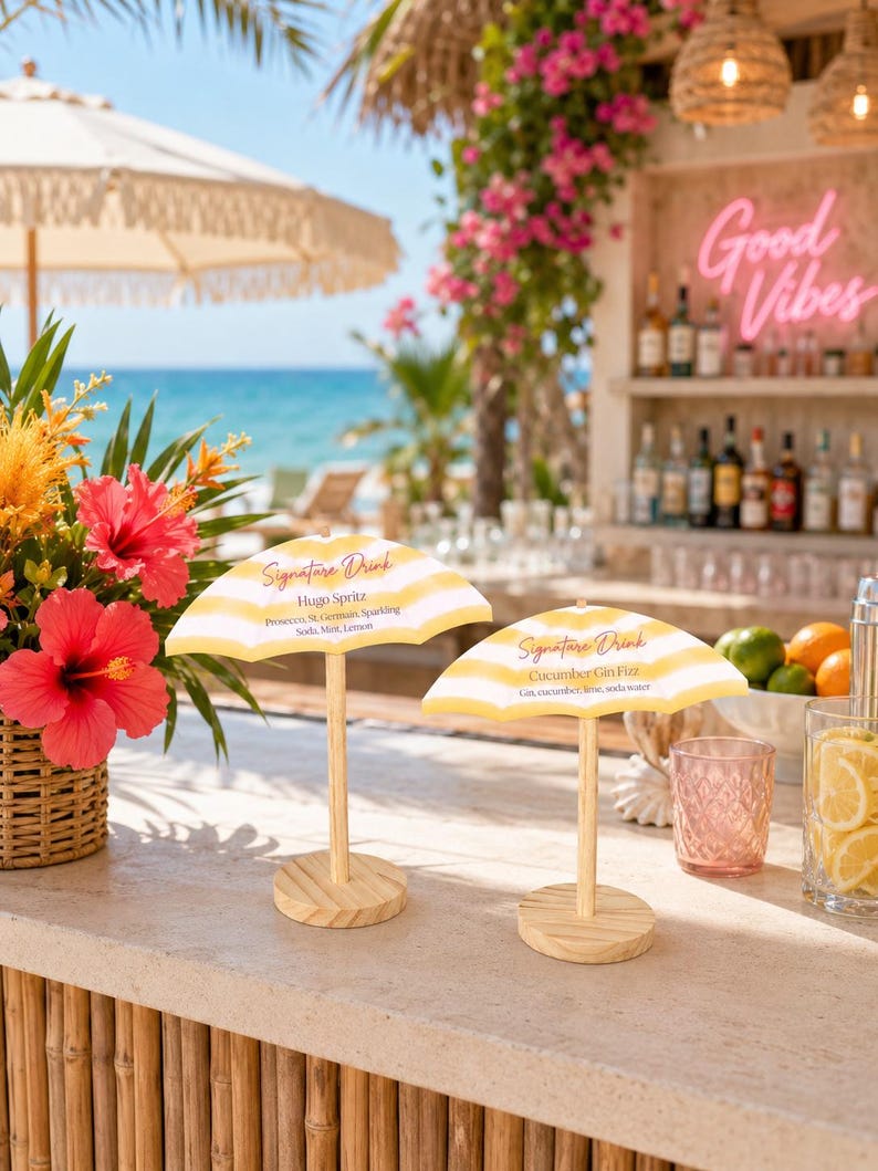 K&ouml;nnte beinhalten: Zwei Miniatur-Cocktailschirm-Schilder mit gelb-wei&szlig;en Streifen auf Holzst&auml;ndern. Das linke Schild tr&auml;gt die Aufschrift Signature Drink Hugo Spritz Prosecco St. Germain Sparkling Soda Mint Lemon. Das rechte Schild tr&auml;gt die Aufschrift Signature Drink Cucumber Gin Fizz Gin cucumber lime soda water.