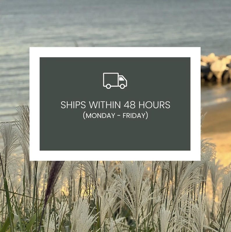 May include: A rectangular sign with a white border and a dark green background. The sign features a white truck icon and the text "SHIPS WITHIN 48 HOURS (MONDAY - FRIDAY)". The background shows tall, feathery plants and a body of water.
