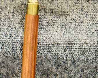 May include: A wooden walking cane with a brass handle featuring a floral design. The cane has a light brown, polished wooden shaft and a brass collar. The handle curves gracefully, offering support and a touch of elegance.