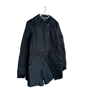 May include: A black double-breasted jacket featuring a wide collar, long sleeves with ribbed cuffs, and two zippered pockets at the waist. The jacket includes a front button closure and is displayed on a white plastic hanger against a white background.