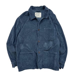 May include: A blue corduroy jacket with a collared neckline, button-up front, and multiple pockets. The jacket has a label that reads "Portuguese Flannel". The jacket is a solid colour and has a textured, ribbed appearance.