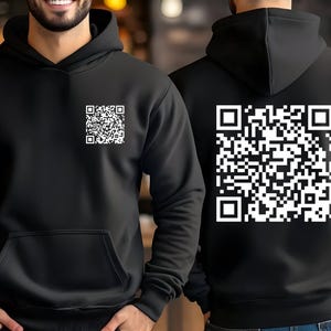 May include: Black hoodie with a front pocket and a hood. The front of the hoodie has a small white QR code, and the back features a larger white QR code. The hoodie is made of a soft material.