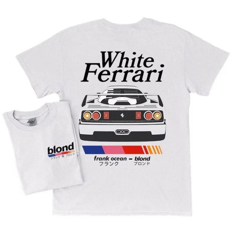 K&ouml;nnte beinhalten: Zwei wei&szlig;e T-Shirts mit grafischen Designs. Eines zeigt eine Autoillustration mit dem Text "White Ferrari". Das andere hat den Text "blond" mit japanischen Schriftzeichen. Beide haben einen Rundhalsausschnitt.