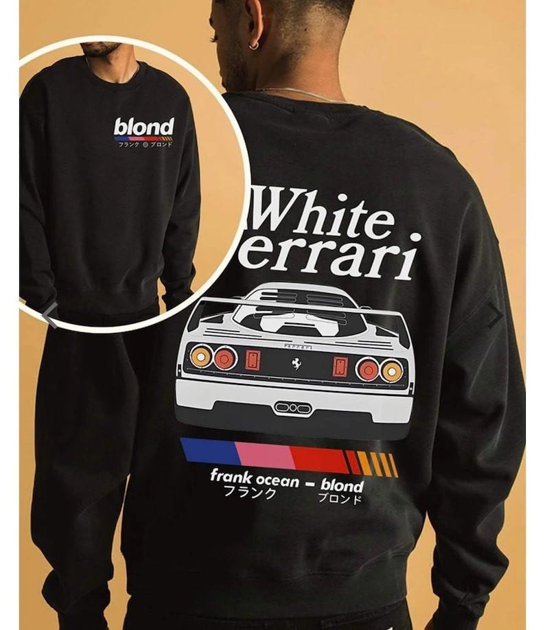 K&ouml;nnte beinhalten: Schwarzes Sweatshirt mit dem Wort "blond" und japanischen Schriftzeichen auf der Vorderseite. Auf der R&uuml;ckseite befindet sich eine wei&szlig;e Ferrari-Grafik, der Text "White. errari", "frank ocean - blond", japanischer Text und ein Farbbalken.