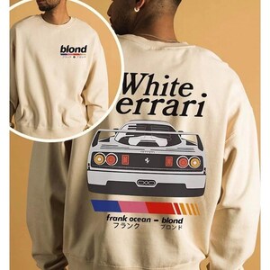 K&ouml;nnte beinhalten: Beiges Sweatshirt mit dem Wort "blond" und japanischem Text auf der Vorderseite. Auf der R&uuml;ckseite steht "White. errari" &uuml;ber einer Autografik, "frank ocean - blond" mit japanischem Text und ein farbenfrohes Streifendesign.
