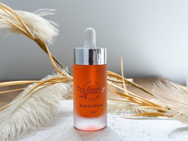May include: A clear glass bottle with a silver cap and dropper, filled with a light orange liquid. The bottle is labeled "Tea Tree Skincare" and "African Tree Oil Serum 30 ml".