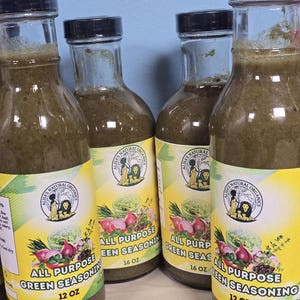 Puede incluir: Cuatro botellas de vidrio de condimento verde con tapas negras. Las etiquetas dicen "Alisa's Natural Organics All Purpose Green Seasoning" con un gráfico de verduras. Dos botellas son de 355 ml, y dos son de 473 ml.