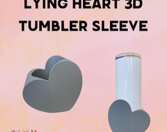 May include: A gray 3D heart-shaped tumbler sleeve and a white tumbler with a gray heart-shaped base. The text "LYING HEART 3D TUMBLER SLEEVE" is displayed in black. The image has a pink background.