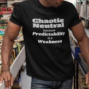 May include: A black t-shirt with white text that reads "Chaotic Neutral because Predictability is a Weakness".