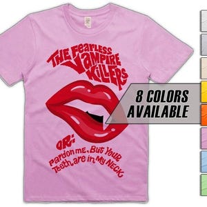 May include: A pale pink t-shirt featuring the words "THE Fearless VAMPIRE KILLERS" in red above a red lip graphic. Below the lip graphic is the text "OR: Pardon me, But Your Teeth are in My NECK". The shirt has "8 COLORS AVAILABLE" in a box.