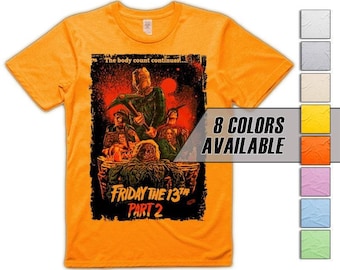 Puede incluir: Camiseta naranja con un gráfico de la película de terror "Viernes 13 Parte 2". El diseño incluye una figura amenazante con un pico, rodeada de otros personajes. El texto en la camiseta dice "The body count continues..." y "Friday the 13th Part 2". Hay ocho colores disponibles.