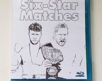 May include: A blue Blu-ray case featuring a white cover with the title "Six-Star Matches" in large text. The cover art depicts two wrestlers, one holding a championship belt. The Blu-ray logo is visible.